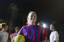 Портрет усміхнений, впевнена молода футболістка з м'ячем — стокове фото
