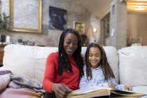 Mutter und Tochter betrachten Fotoalbum auf Sofa — Stockfoto