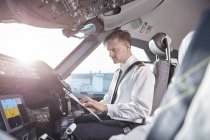 Male pilot with clipboard preparing in airplane cockpit — Stock Photo