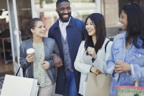 Smiling friends with coffee and shopping bags — Stock Photo