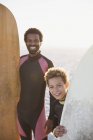 Retrato sorrindo pai e filho com pranchas de surf na praia ensolarada de verão — Fotografia de Stock