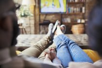 Casal afetuoso de mãos dadas, assistindo TV na sala de estar — Fotografia de Stock