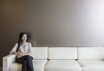 Porträt lächelnde Geschäftsfrau auf Sofa im modernen Büro — Stockfoto