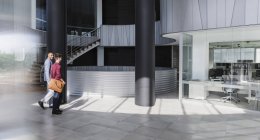 Empresários caminhando no moderno lobby de escritório — Fotografia de Stock