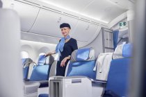 Asistente de vuelo femenina con confianza en retratos en el avión - foto de stock