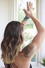 Donna serena con tatuaggio che pratica yoga con le mani strette sopra la testa — Foto stock