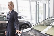 Portrait confident car saleswoman in car dealership showroom — Stock Photo