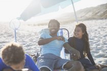Padre ridente e bambini che si rilassano sulla soleggiata spiaggia estiva — Foto stock