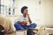 Satisfied woman drinking coffee and painting living room — Stock Photo