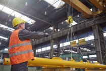 Arbeiter führt Hydraulikkran in Fabrik — Stockfoto