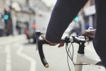 Mains sur l'homme sur le guidon de vélo, se déplacer sur la rue urbaine ensoleillée — Photo de stock