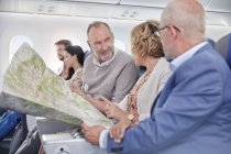 Ältere Freunde schauen sich Karte im Flugzeug an — Stockfoto