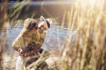 Прихильна молода пара обіймається на сонячному літньому березі річки — стокове фото