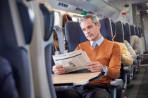 Uomo d'affari che legge il giornale sul treno passeggeri — Foto stock