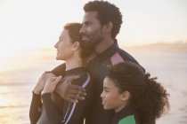 Serena família afetuosa olhando para longe na praia do pôr do sol verão — Fotografia de Stock