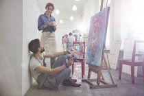 Artistas bebendo café pintura no cavalete em estúdio de classe de arte — Fotografia de Stock