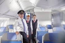 Piloto e comissários de bordo confiantes em retratos no avião — Fotografia de Stock