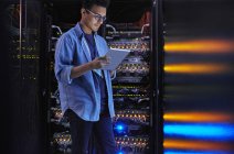 Fokussierte männliche IT-Techniker mit digitalem Tablet am Panel in dunklen Serverraum — Stockfoto