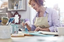 Mature female artist painting picture frames in art studio — Stock Photo