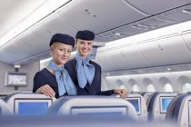 Улыбающиеся портреты, уверенные в себе стюардессы в самолете — стоковое фото