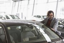 Homme client regardant nouvelle voiture dans le concessionnaire automobile showroom — Photo de stock