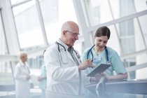 Médico y enfermera con tableta digital hablando en el hospital - foto de stock