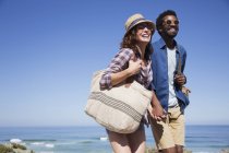 Smiling, affectionate couple holding hands on sunny summer ocean beach — Stock Photo