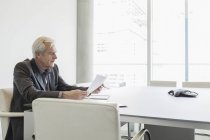 Uomo d'affari anziano che rivede i documenti in sala conferenze — Foto stock