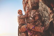 Alpiniste masculin concentré suspendu à la roche — Photo de stock
