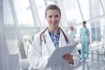 Portrait smiling, confident female doctor with clipboard in hospital — Stock Photo
