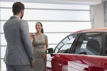 Vendedor de carro dando chaves para carro novo para cliente feminino na concessionária de carro — Fotografia de Stock
