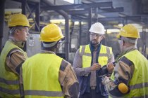 Supervisor talking with steelworkers in steel mill — Stock Photo