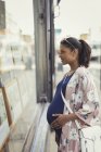 Pregnant woman browsing real estate listings at storefront — Stock Photo