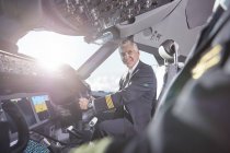 Улыбающиеся пилоты разговаривают в кабине самолета — стоковое фото
