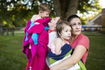 Madres lesbianas sosteniendo a niños mojados envueltos en una toalla en el patio de verano - foto de stock