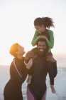 Happy family in wet suits on summer sunset beach — Stock Photo