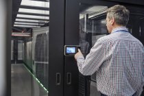 Специалист по информационным технологиям вводит код безопасности в дверь серверной комнаты — стоковое фото