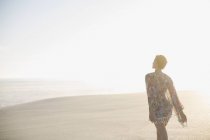 Mulher serena em maiô camuflado andando na praia ensolarada de verão — Fotografia de Stock