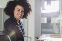 Porträt lächelnde, selbstbewusste Geschäftsfrau im sonnigen Büro — Stockfoto