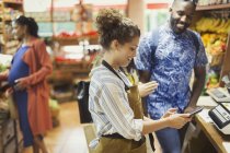 Kassiererin mit Taschenrechner hilft männlicher Kundin im Supermarkt — Stockfoto