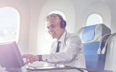 Бизнесмен в наушниках смотрит кино на самолете — стоковое фото