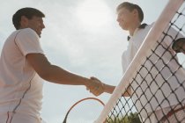 Young male tennis players handshaking in sportsmanship at net — Stock Photo