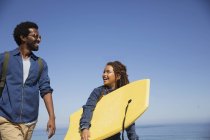Father and daughter carrying boogie board on sunny summer beach — Stock Photo