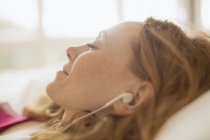 Primer plano mujer serena con auriculares escuchando música - foto de stock