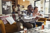 Male friends drinking beer and playing video game in living room — Stock Photo