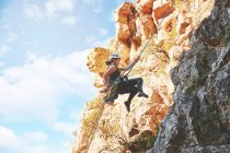 Female rock climber descending rocks — Stock Photo