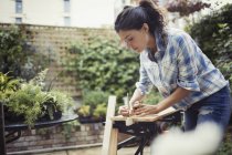 Junge Frau misst und markiert Holz auf Terrasse — Stockfoto