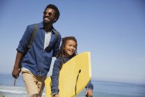 Smiling father and daughter with boogie board on sunny summer ocean beach — Stock Photo