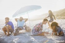 Multi-ethnic family relaxing and playing on sunny summer beach — Stock Photo