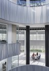 Geschäftsleute treffen sich an einem Tisch im architektonischen, modernen Büro-Atrium — Stockfoto